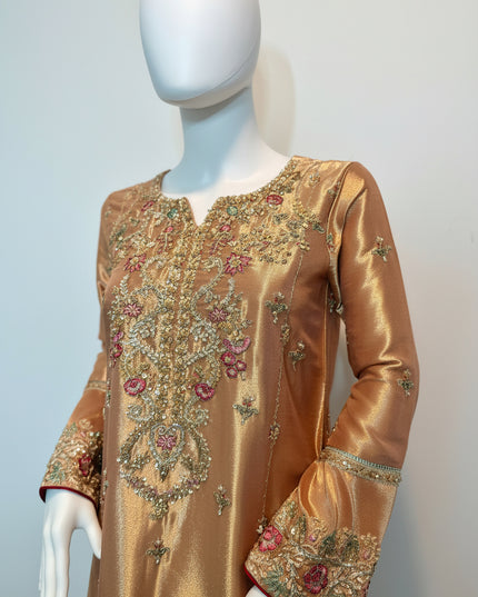 Gold embroidered dress on a mannequin against a light gray background