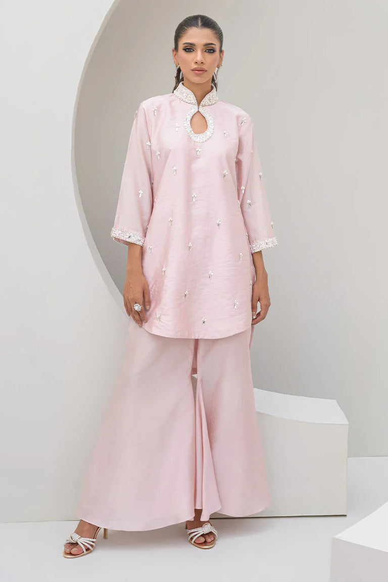 Woman wearing a light pink traditional outfit with a white background