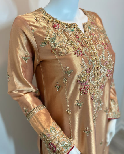 Gold embroidered dress on a mannequin against a plain background