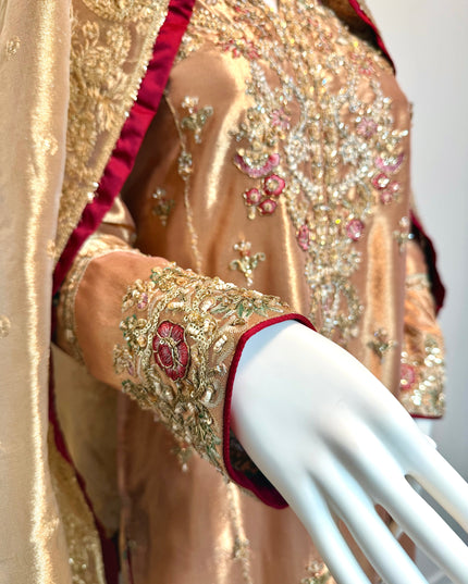 Close-up of a gold embroidered garment on a mannequin arm.