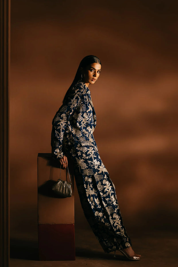 Woman in a floral dress holding a handbag against a brown background