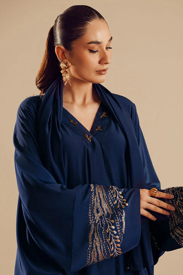 Woman wearing a navy blue outfit with intricate patterns on a beige background
