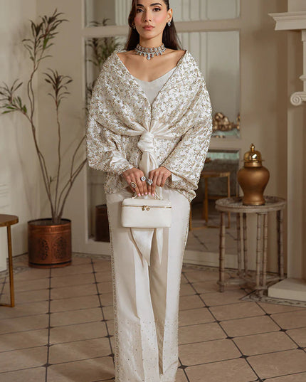 Woman in a stylish outfit standing in an elegant room with decorative elements.