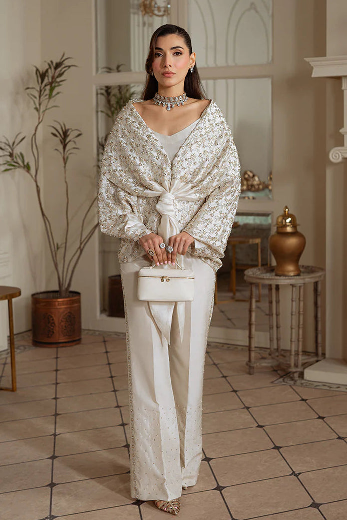 Woman in a stylish outfit standing in an elegant room with decorative elements.