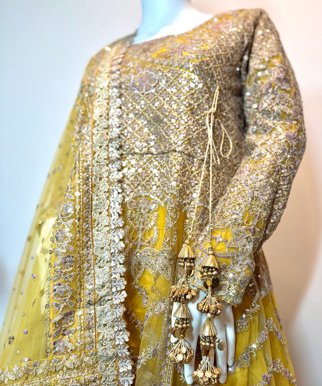 Yellow embroidered outfit with intricate patterns on a mannequin against a plain background