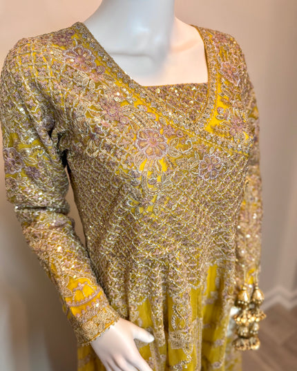 Mannequin wearing a yellow and gold embroidered dress with floral patterns.