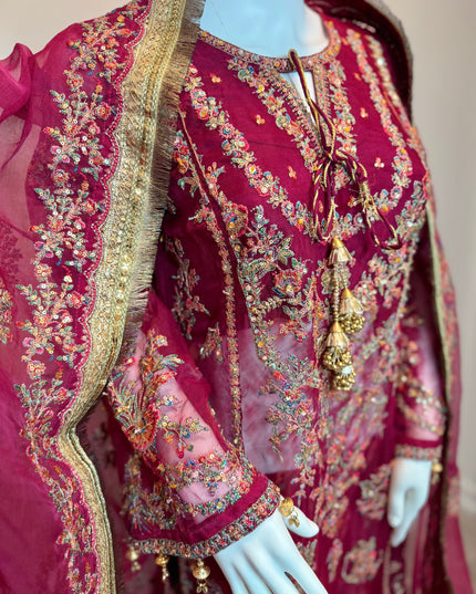 Maroon embroidered traditional outfit on a mannequin with gold and multicolor details.