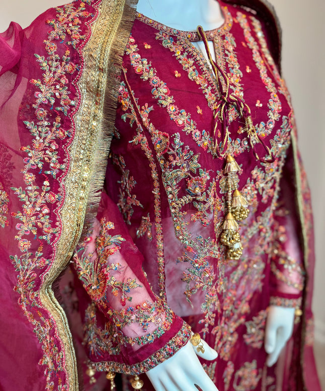 Maroon embroidered traditional outfit on a mannequin with gold and multicolor details.