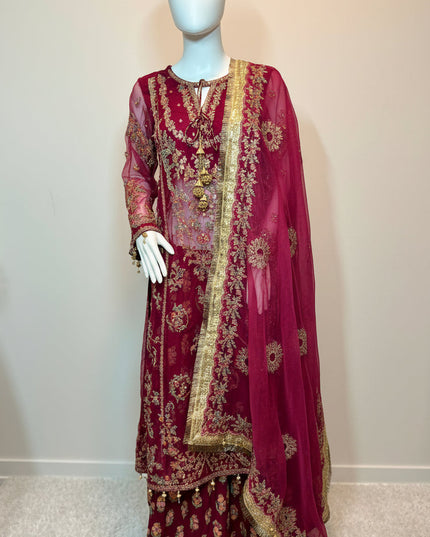 Maroon embroidered traditional outfit on a mannequin against a white wall.