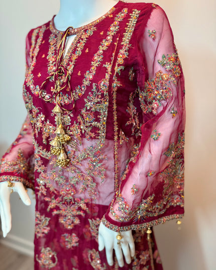 Decorative red garment with intricate gold and multicolor embroidery on a mannequin.