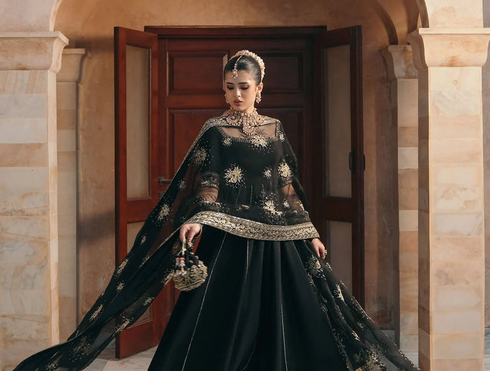 Woman in a black and gold traditional outfit standing in front of an archway.