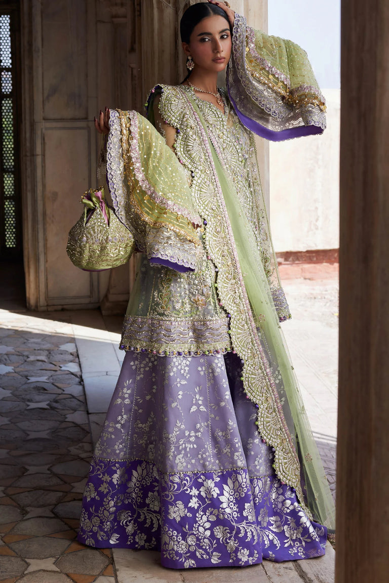 Woman in a traditional outfit with green and purple elements, standing in an outdoor setting.