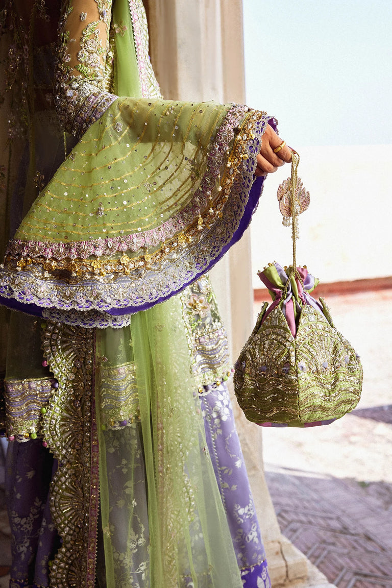 Person wearing a green and gold traditional outfit with a matching handbag.
